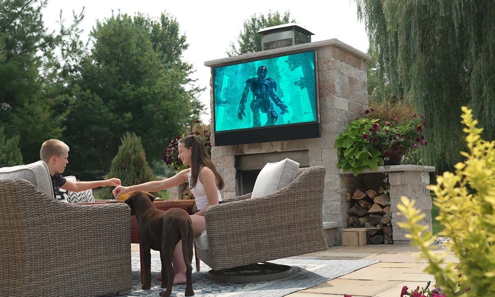 a couple plays games on their patio while a movie plays behind them