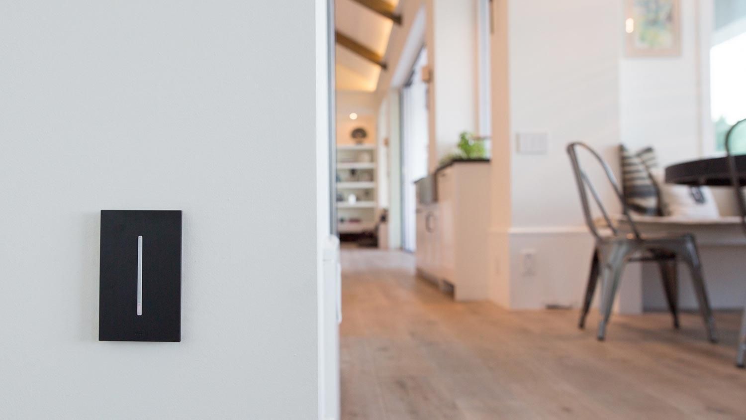 black keypad on a white wall and an out of focus room behind it