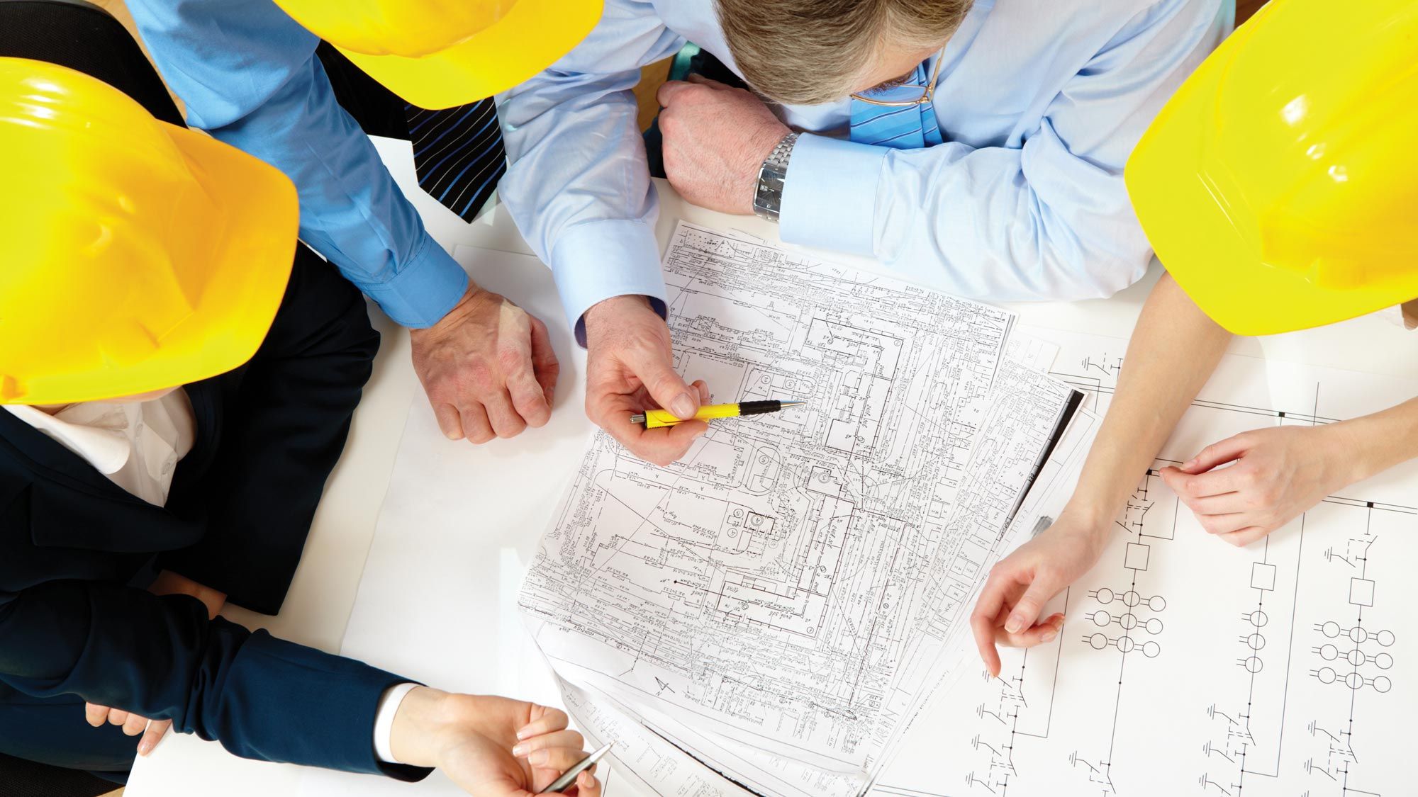 a group of architects standing around blueprints in hardhats