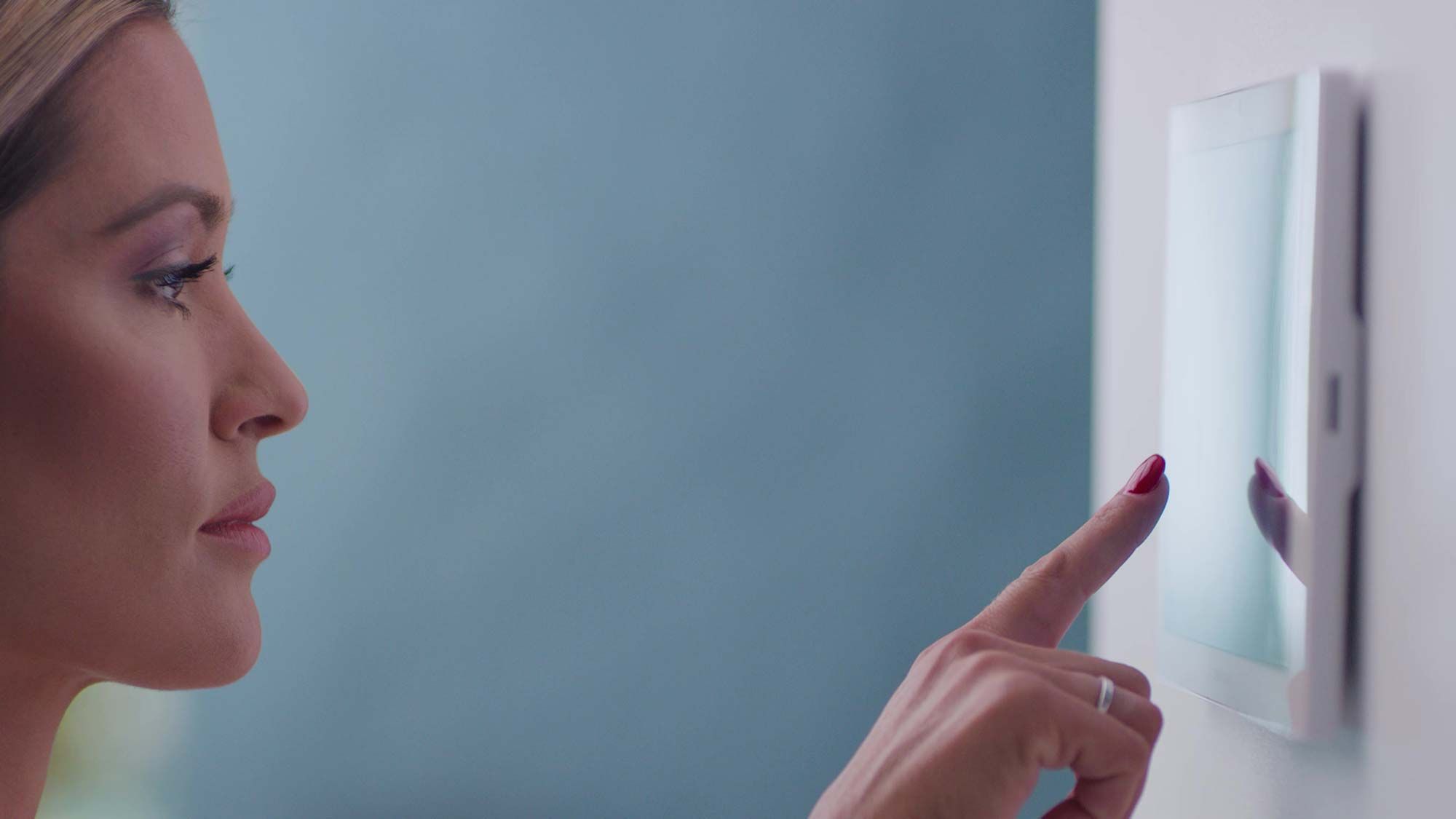 woman interacting with wall-mounted touchpad